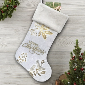Detail of white velvet Christmas stocking with golden holly print and faux fur cuff