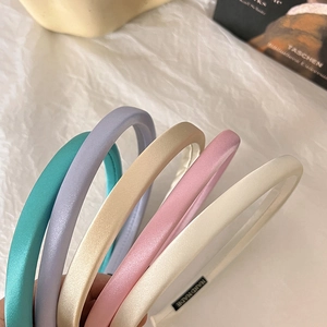 Detail of colorful satin fabric headbands showing handmade labels and sleek texture