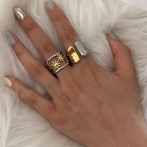 Detailed shot of two-tone open ring and gold floral hollow band on white plush