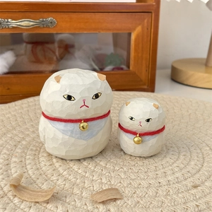 Detailed macro of hand-carved white wooden cat statues with red cords and gold bells