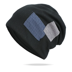 Dettaglio del berretto nero in maglia a nido d'ape con patch in tessuto blu e grigio
