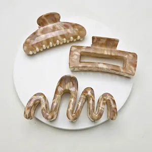 Three-piece amber marble claw clip set in various shapes on a white display tray