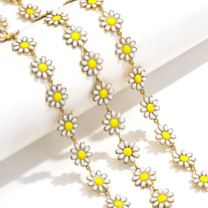 Detailed close-up of yellow and white enamel daisy chain links on golden base