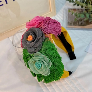 Detail of yellow fabric headband featuring layered net yarn flowers and hanging tassels