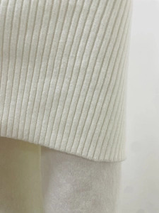Detailed close-up of premium ribbed knit texture on an elegant white sweater dress