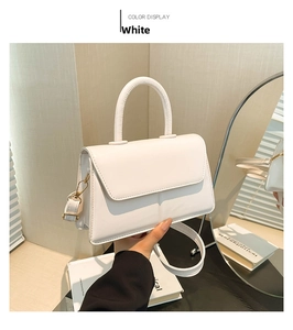 Detail of minimalist white square handbag with glossy leather finish and gold hardware
