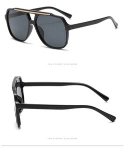 Close-up of black aviator sunglasses featuring a gold textured double bridge detail