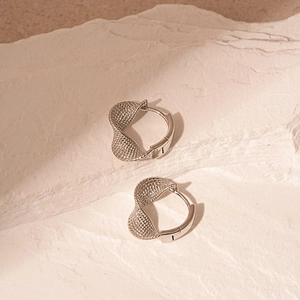Silver twisted woven texture geometric hoop earrings on a minimalist stone background