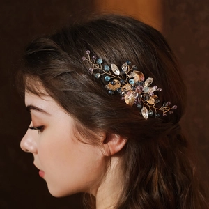 Dettaglio di pettine da sposa in filo d'oro con cristalli viola e foglie nei capelli