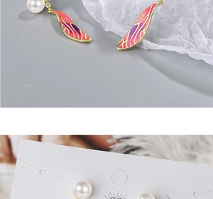 Macro detail of long wing drop earrings with pink-purple gradient enamel and white pearls