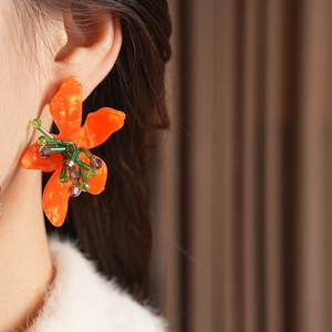Macro view of vintage orange floral earrings with green and purple beaded details