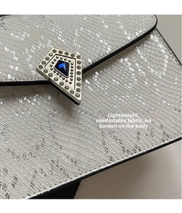 Close-up of white snakeskin texture with a blue gemstone pentagonal metal buckle