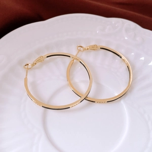 Detailed macro shot of 14k gold plated hoop earrings with black enamel and zircons