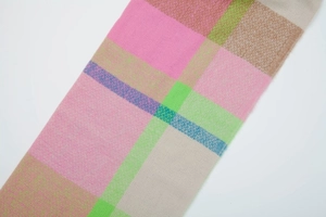 Macro detail of the soft woven texture and colorful plaid pattern on this winter scarf