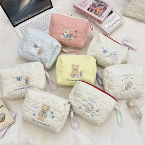 Flat lay of quilted cartoon cosmetic bags with animal embroidery and colorful zippers