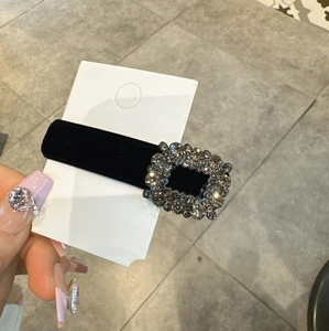 Primo piano di un fermaglio per capelli in velluto nero con una lussuosa fibbia quadra di strass