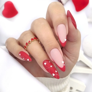 French almond fake nails with red heart patterns and dots on a nude base design