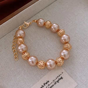 Detail of champagne pearl bracelet with hollow gold beads and lobster clasp on linen cloth