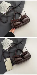 Detail of dark brown glossy patent leather saddle bag with double front flap pockets