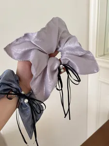 Détail de chouchous en tissu scintillant avec rubans noirs et accents de perles