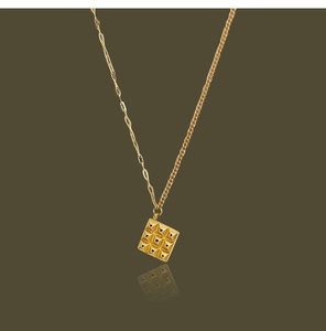 Detailed view of square gold chocolate pendant with asymmetric chain and star pattern
