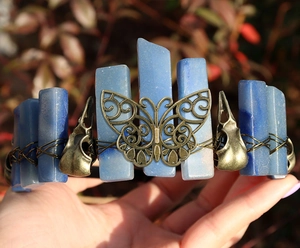 Macro detail of gothic crown with blue crystals, bronze butterfly and animal skulls
