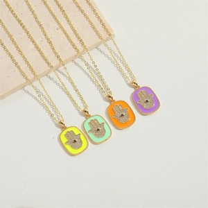 Colorful Hamsa Hand enamel pendants on gold necklaces with rhinestones on white stone base