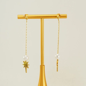 Close-up of golden long tassel earrings with white pearls and octagonal star pendants