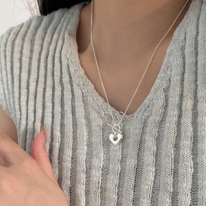 Detail of silver heart necklace with OT toggle clasp worn on a knitted sweater