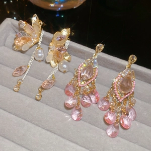 Close-up of crystal butterfly tassel earrings with pearls and pink teardrop stones