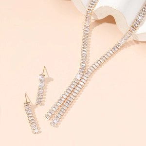 Macro shot of gold necklace and drop earrings with rectangular cut clear zircons