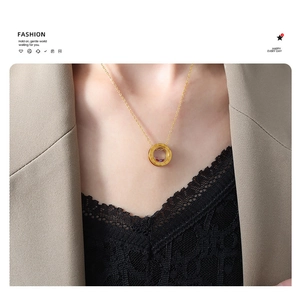 Detail of gold necklace with double circular pendant and roman numerals on model