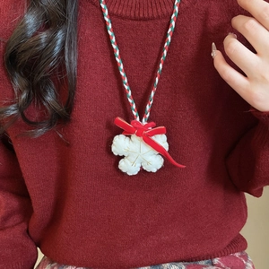 Detail of plush snowflake pendant with red bow and tri-color braided rope necklace