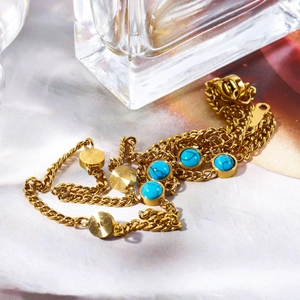 Detail of layered gold necklace featuring turquoise stones and circular golden pendants