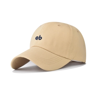 Détail d'une casquette en coton beige avec broderie 'ab' bleue et visière incurvée