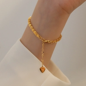 Minimalist gold titanium steel phoenix tail bracelet with heart pendant on female wrist