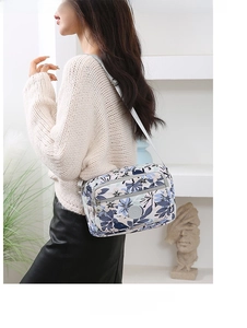 Detail of multi-compartment crossbody bag with floral pattern and adjustable shoulder strap