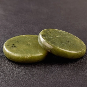 Detailed macro view of two polished green jade discs showing natural textures and gloss