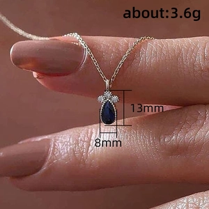 Elegante collana d'oro con ciondolo blu zaffiro a forma di pera e cristalli luminosi