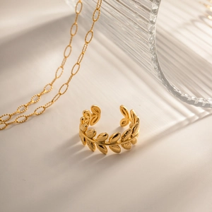 Close-up of golden olive branch leaf open ring on an elegant minimalist background