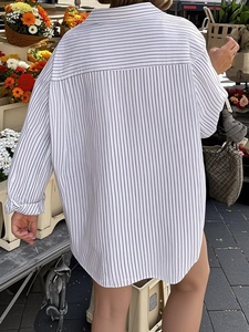 Back view of a loose-fit striped long-sleeve shirt with yoke detail in a natural setting
