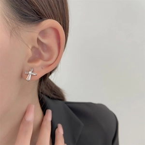 Close-up of minimalist silver cross stud earring with rectangle cut zircons on ear