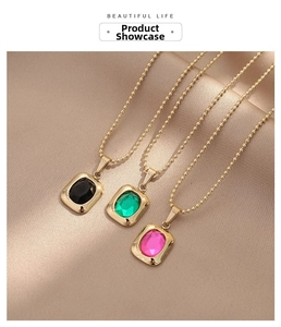 Detailed view of three gold bead necklaces with emerald green, black, and pink gemstones