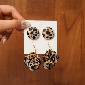 Close-up of leopard print fabric flower and round stud earrings set held on a card