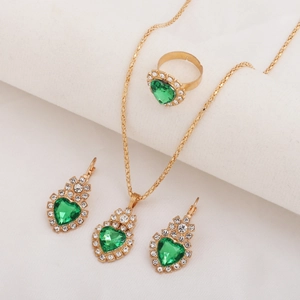 Detailed view of bridal jewelry set with green heart gems and crystals in gold setting