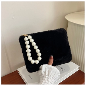 Close-up of black plush handbag with large white pearl handle and gold metal clasp