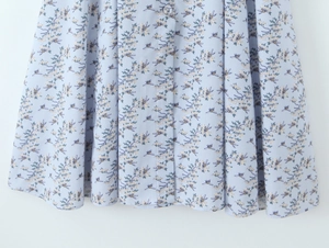 Detail of light blue floral dress with bee pattern and single-breasted button placket
