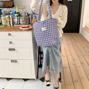 Detailed view of purple cloud bubble texture tote bag carried by a model in casual wear