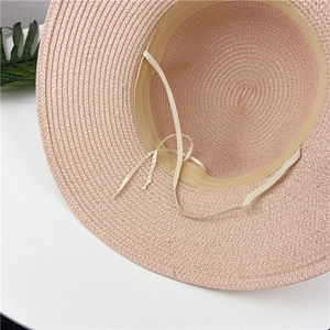 Detail of pink woven straw hat showing adjustable drawstring and elastic wind lanyard