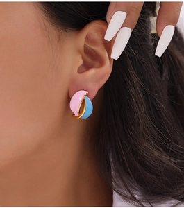 Close-up of pink and blue enamel leaf earrings on model with golden metal edges